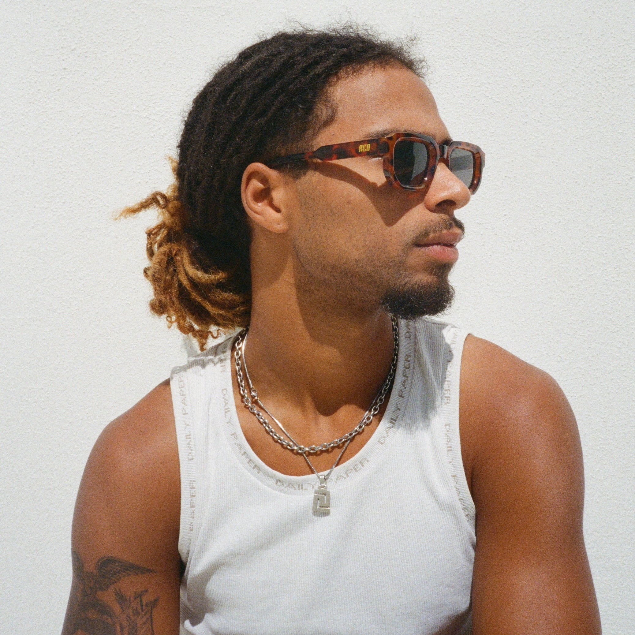 Man wearing reo sunglasses retroframe and a white tank top against a light background